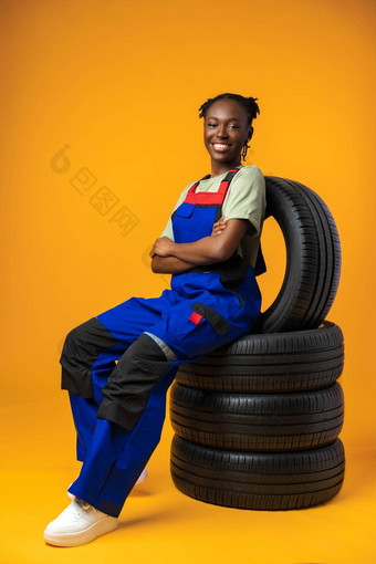 肖像微笑黑色的女机械师摆姿势车轮胎工作室