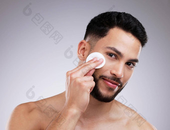 碳粉帮助最小化毛孔拍摄年轻的男人。应用产品脸棉花垫