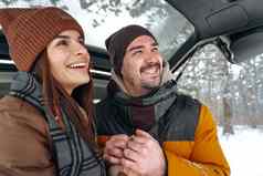 可爱的微笑夫妇坐着车树干冬天森林