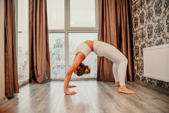 年轻的运动有吸引力的女人练习瑜伽作品<strong>首页</strong>瑜伽工作室<strong>运动服</strong>装白色裤子全身的前在室内健康的生活方式概念