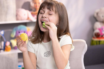 年轻的浅黑肤色的女人孩子女孩使决定选择macaron咬左柠檬beryy填充使阿月浑子奶油咬macaron绿色颜色