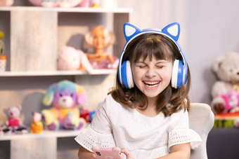 可爱的小孩子女孩耳机有趣的编辑应用程序智能手机享受很酷的视频音乐内容社会网络玩在线游戏沟通距离的远近