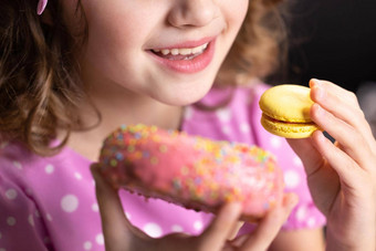 高加索人孩子学校女孩吃甜甜圈macaron时间可爱的孩子女孩咬一块甜甜圈macaron坐着表格首页甜蜜的上瘾概念