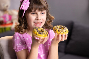 快乐的学校女孩玩蛋糕在室内有趣的少年女孩有趣的色彩斑斓的甜甜圈现代首页肖像甜蜜的女孩选择甜甜圈首页房间