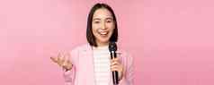 图像热情的亚洲女商人给演讲会说话的麦克风持有小站西装粉红色的工作室背景