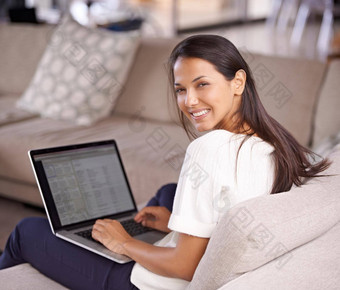 悠闲的浏览沙发上拍摄有吸引力的年轻的女人坐着沙发上移动PC
