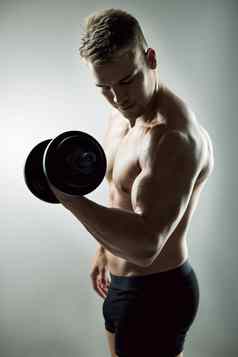 权重日期工作室拍摄肌肉发达的年轻的男人。锻炼哑铃灰色背景