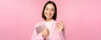 肖像企业女人女孩办公室业务西装持有数字平板电脑显示推荐公司站粉红色的背景