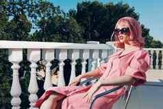迷人的女人粉红色的衣服现代风格站栏杆生活方式
