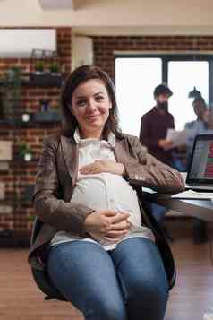 微笑怀孕了金融公司女商人坐着桌子上办公室工作空间相机