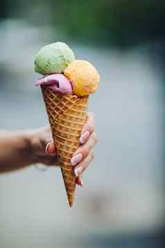 女人持有美味的色彩斑斓的冰奶油夏季共鸣甜蜜的食物