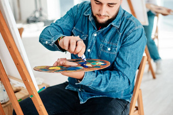 蓝色的裁剪拍摄英俊的年轻的艺术家挤压油漆调色板艺术类工作室