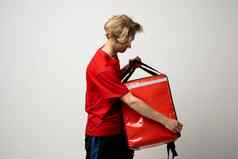 年轻的快递开放热袋白色背景食物交付服务交付的家伙红色的t恤统一的工作快递持有红色的热食物背包服务概念