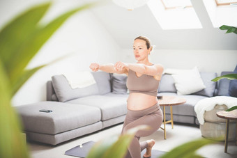 年轻的美丽的怀孕了女人培训普拉提首页生活房间健康的生活方式活跃的怀孕母亲概念