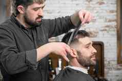 理发师切割头发剪刀英俊的年轻的男人。