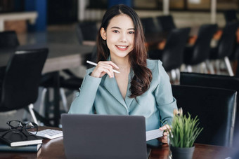 亚洲女人企业家女商人显示微笑脸阅读书发展中金融投资策略操作电脑平板电脑工作木表格