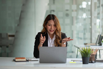 肖像微笑亚洲女人挥舞着会说话的视频<strong>调用</strong>成功的年轻的女人坐着白色西装业务会议移动PC