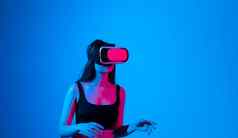 快乐的女孩手穿虚拟现实护目镜玩游戏霓虹灯光未来技术概念元宇宙