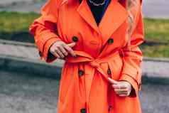 时尚金发女郎女人穿橙色外套蓝色的珍妮丝白色啃食者neckchain摆姿势街