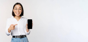 热情的年轻的亚洲女人指出手指智能<strong>手机</strong>屏幕显示广告移动电话白色背景