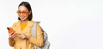 时尚的年轻的亚洲女人旅游旅行者背包智能<strong>手机</strong>微笑相机摆姿势白色背景