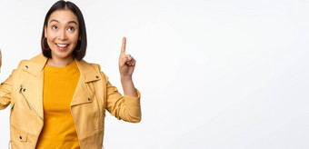 图像微笑亚洲浅黑肤色的女人女人指出手指显示广告快乐脸摆姿势白色背景