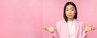 肖像困惑亚洲女商人耸肩膀笨困惑不要站粉红色的背景办公室西装