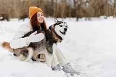 年轻的女人雪玩狗有趣的友谊新鲜的空气