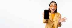 热情的亚洲女模型显示智能手机应用程序接口在线商店网站移动电话屏幕站白色背景
