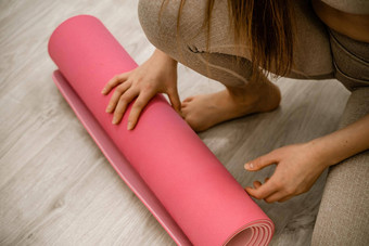 年轻的女人卷粉红色的健身瑜伽席锻炼锻炼首页生活房间瑜伽工作室<strong>健康</strong>的<strong>习惯</strong>适合重量损失概念特写镜头照片