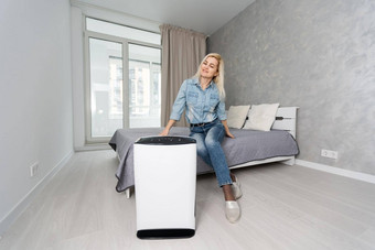 女人把现代空气净化器生活房间空气净化器受欢迎的设备家庭电空气净化器净化空气