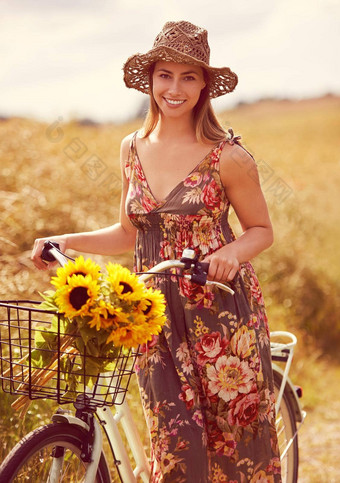 自行车伟大的在户外拍摄年轻的女人骑自行车农村群向日葵