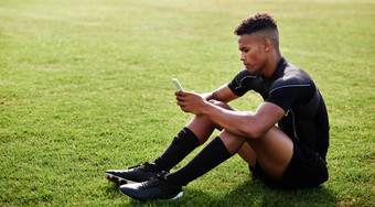 无线网络热技能拍摄年轻的男人。坐着场智能手机橄榄球匹配