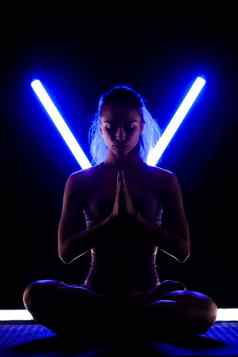 适合女人练习瑜伽提出了轮廓女孩锻炼工作室黑色的背景形状的霓虹灯蓝色的紫色的领导管光