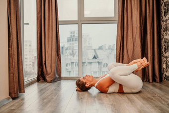 年轻的运动有吸引力的女人练习瑜伽作品首页瑜伽工作室运动服装白色裤子全身的前在室内健康的生活方式概念