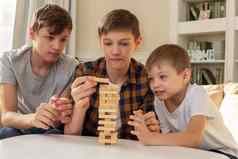 青少年男孩兄弟玩董事会游戏使木矩形块拉块塔