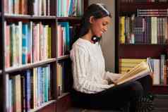 令人兴奋的章拍摄年轻的女人阅读书坐着地板上书架上图书馆