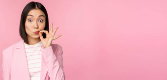 肖像亚洲企业女人显示口密封关闭关闭嘴唇关键手势承诺秘密站粉红色的背景西装