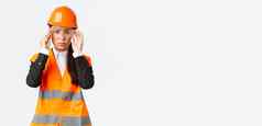 严肃的表情年轻的亚洲女建设经理遵循安全协议穿保护眼镜头盔进入企业站白色背景