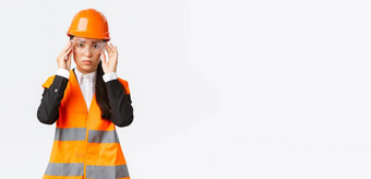 严肃的表情年轻的亚洲女建设经理遵循安全协议穿保护眼镜头盔进入企业站白色背景