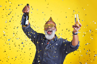 时间庆祝肖像快乐的高级男人。庆祝喝香槟工作室黄色的背景