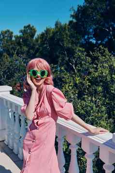 快乐的女人绿色眼镜粉红色的衣服摆姿势在户外