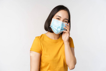 科维德疫苗接种医疗保健概念可爱的亚洲女孩医疗脸面具显示乐队援助冠状病毒疫苗接种站白色背景