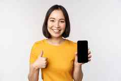 技术人概念微笑年轻的女人显示拇指智能手机屏幕移动电话应用程序接口站白色背景