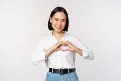 爱手势美丽的亚洲年轻的女人显示心手势微笑表达护理感情站白色背景