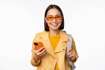 时尚的年轻的亚洲女人旅游旅行者背包智能手机微笑相机摆姿势白色背景