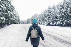 女孩灰色的外套灰色的背包走一边冬天路冬天森林松树