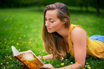 阅读引人入胜的故事拍摄无忧无虑的年轻的女人放松场草书