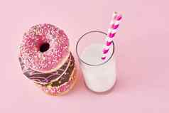堆栈色彩斑斓的甜甜圈装饰玻璃牛奶粉红色的背景