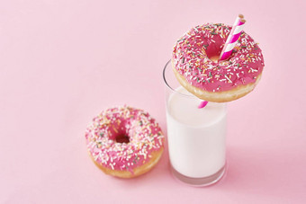 甜甜圈装饰糖衣撒上玻璃牛奶粉红色的背景